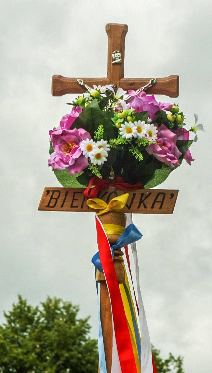 Krzyż z kwiatami i wstążkami.