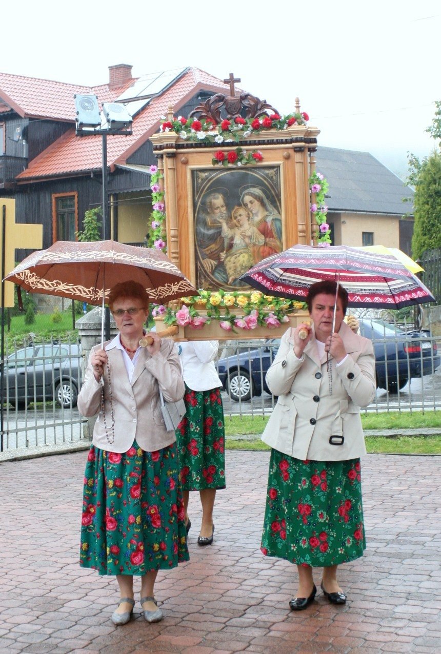 Panie w strojach regionalnych z parasolami.