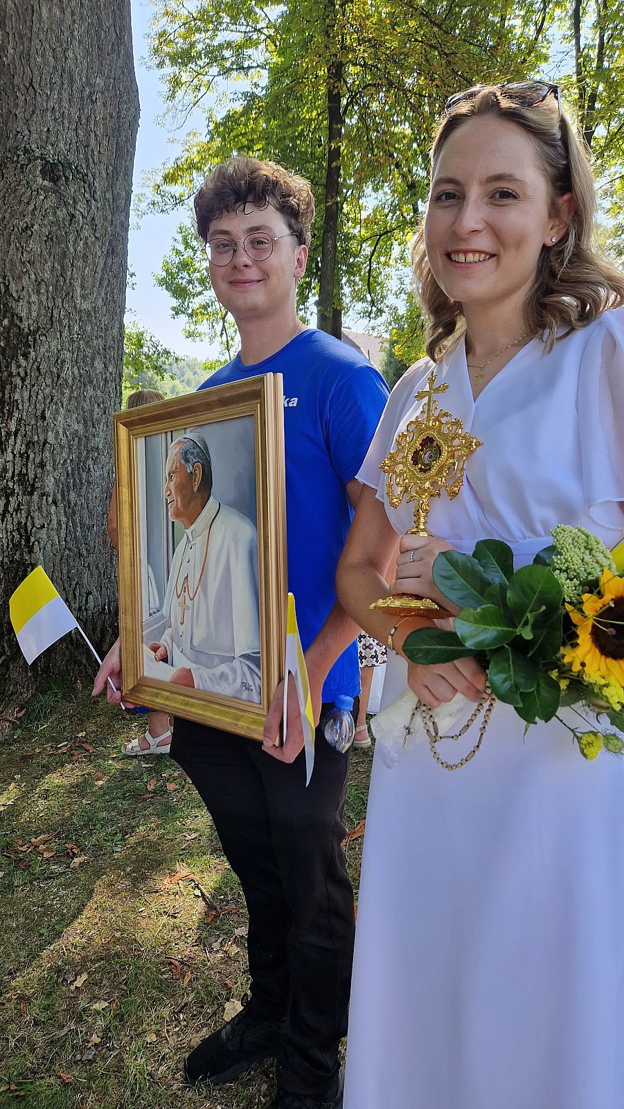 Obraz św. Jana Pawła II i relikwiarz w rękach asysty.