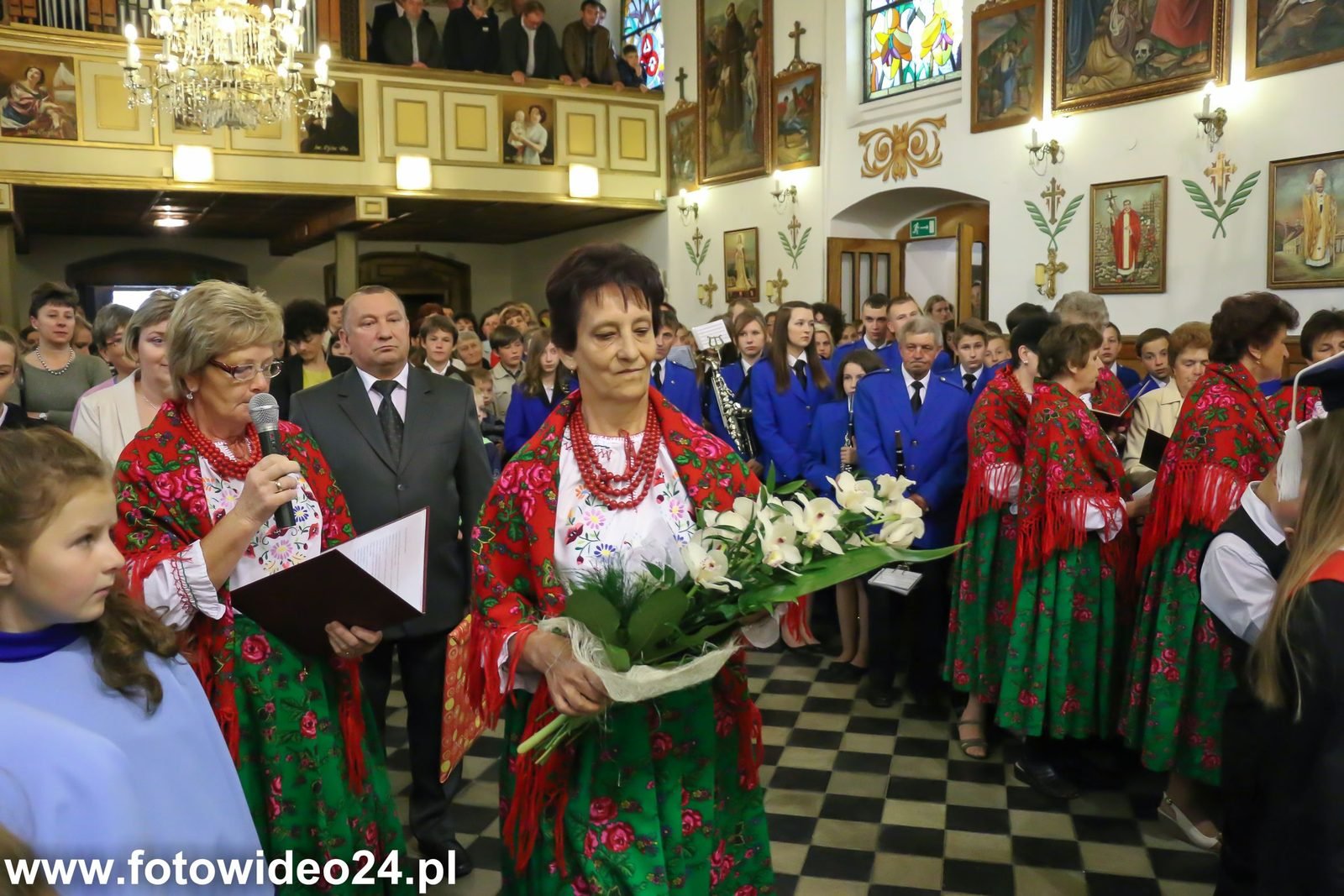 Panie w strojach regionalnych z kwiatami.