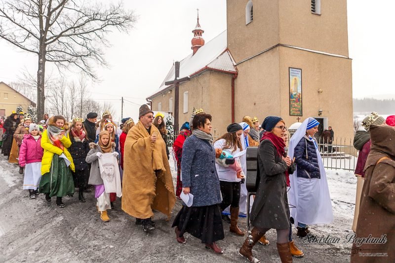 Orszak idzie zaśnieżoną drogą.