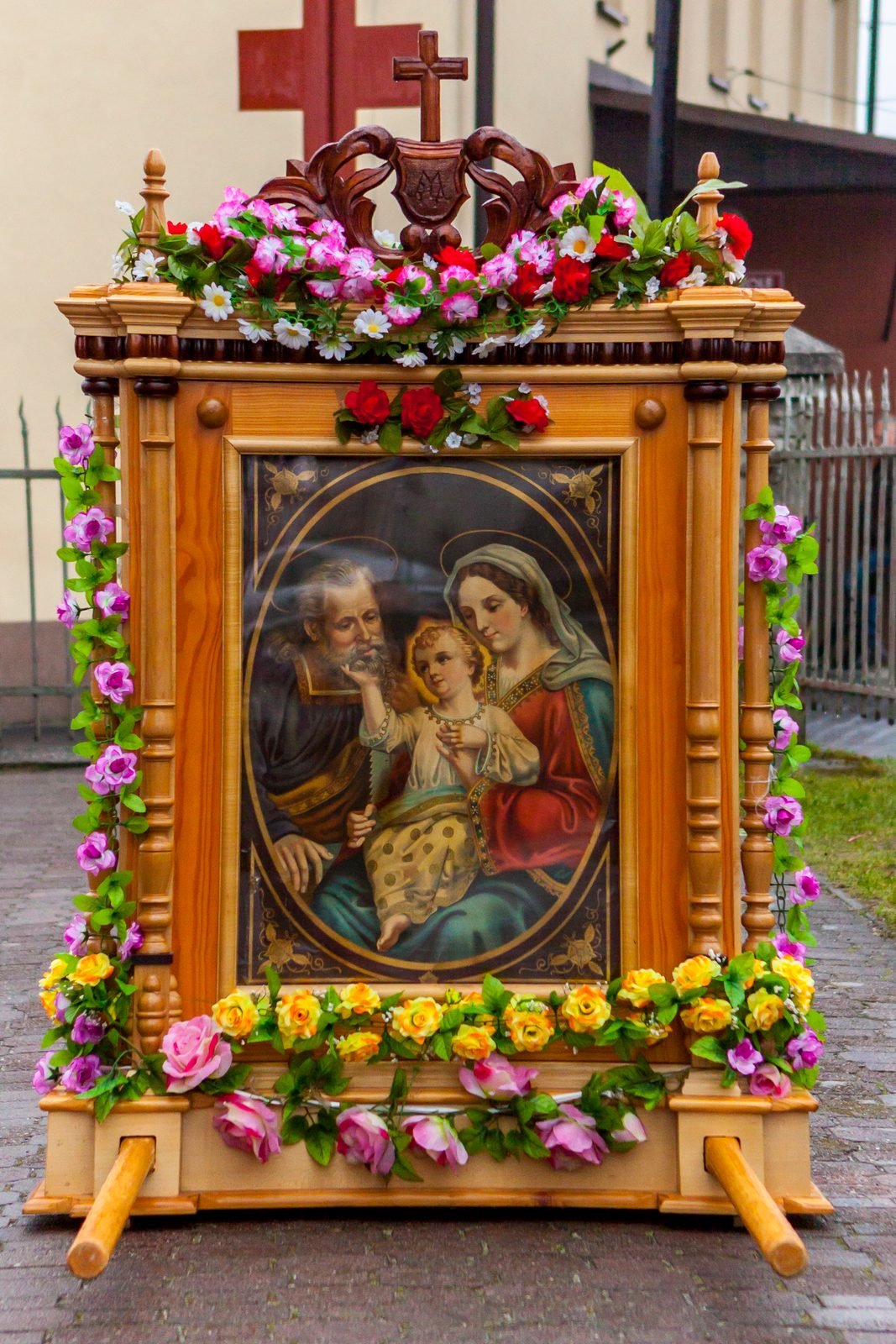 Feretron z obrazem Świętej Rodziny w kwiatach.