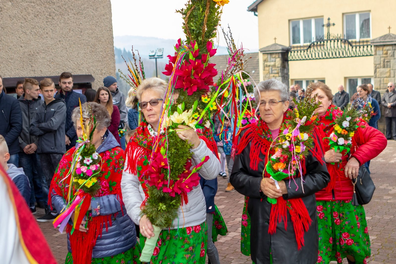 Panie w strojach regionalnych z palmami.