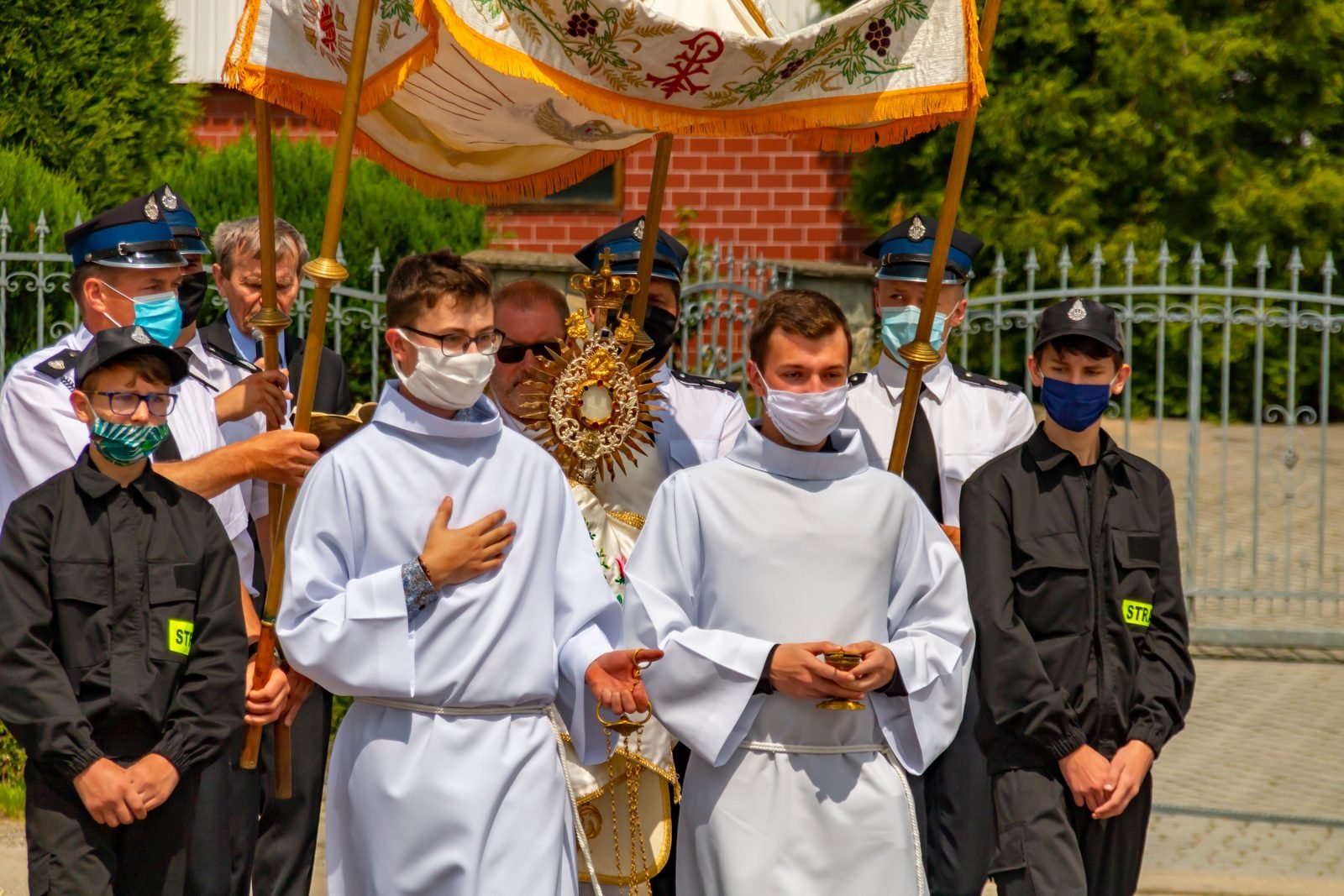 Ministranci i strażacy przy baldachimie.