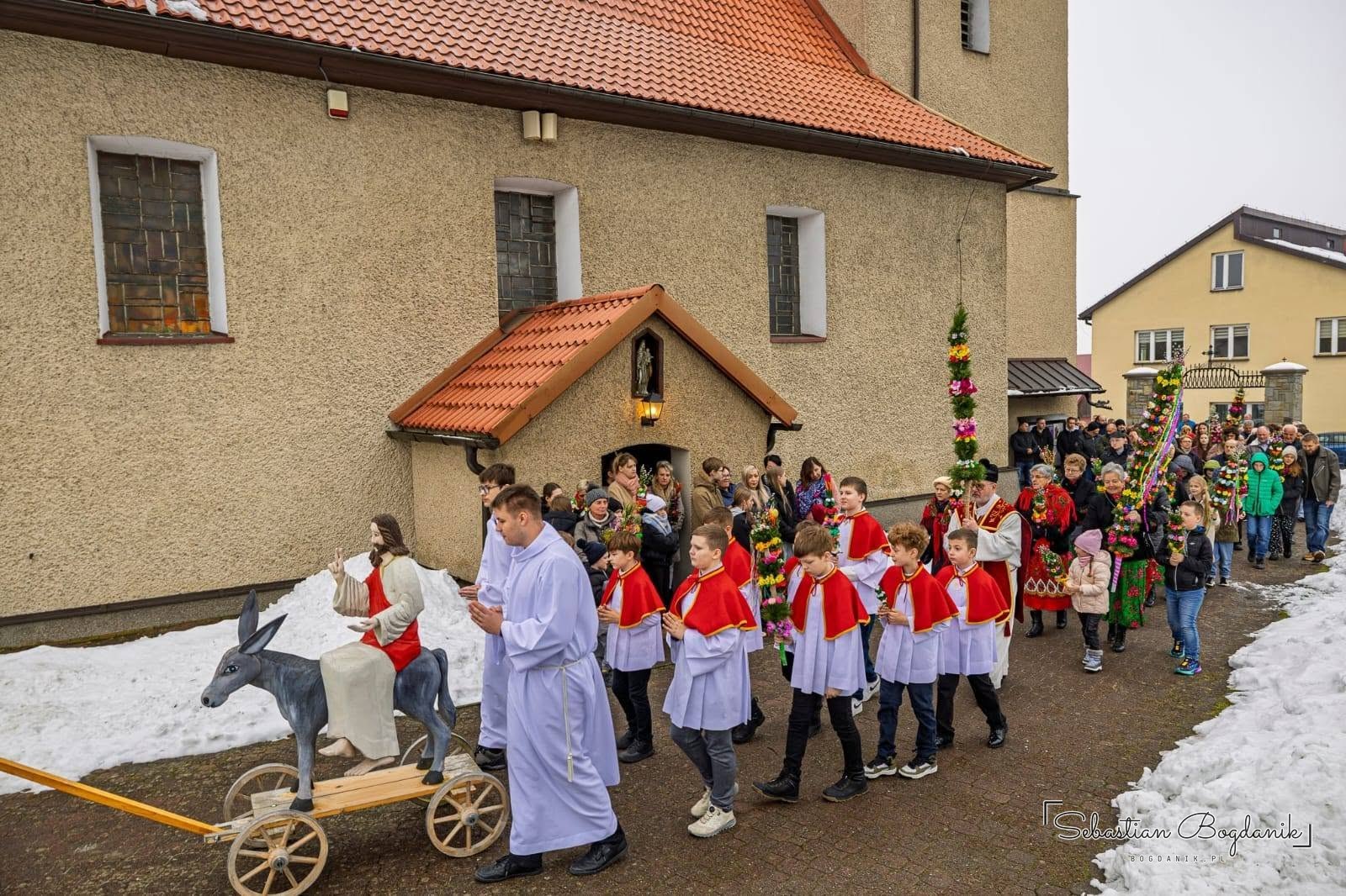 Procesja Niedzieli Palmowej z drewnianym osiołkiem przy kościele w Bieńkówce.