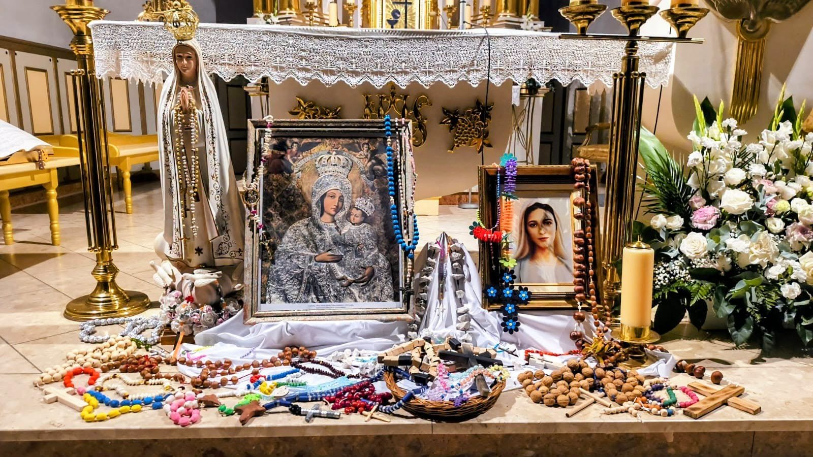 Różańce wykonane przez dzieci i rodziców, złożone przed ołtarzem obok figury Matki Bożej Fatimskiej.